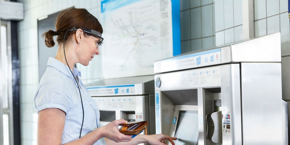 A woman wearing Tobii Pro Glasses 2 buys tickets from a ticket machine.